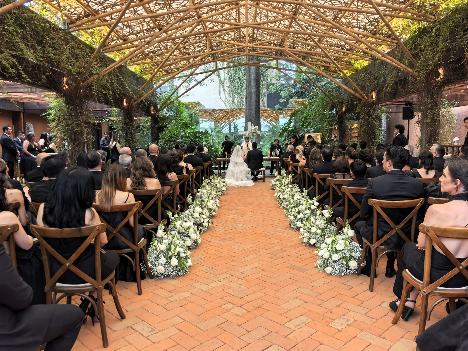 Ceremonia de boda en un jardín con la novia, el novio y sus invitados