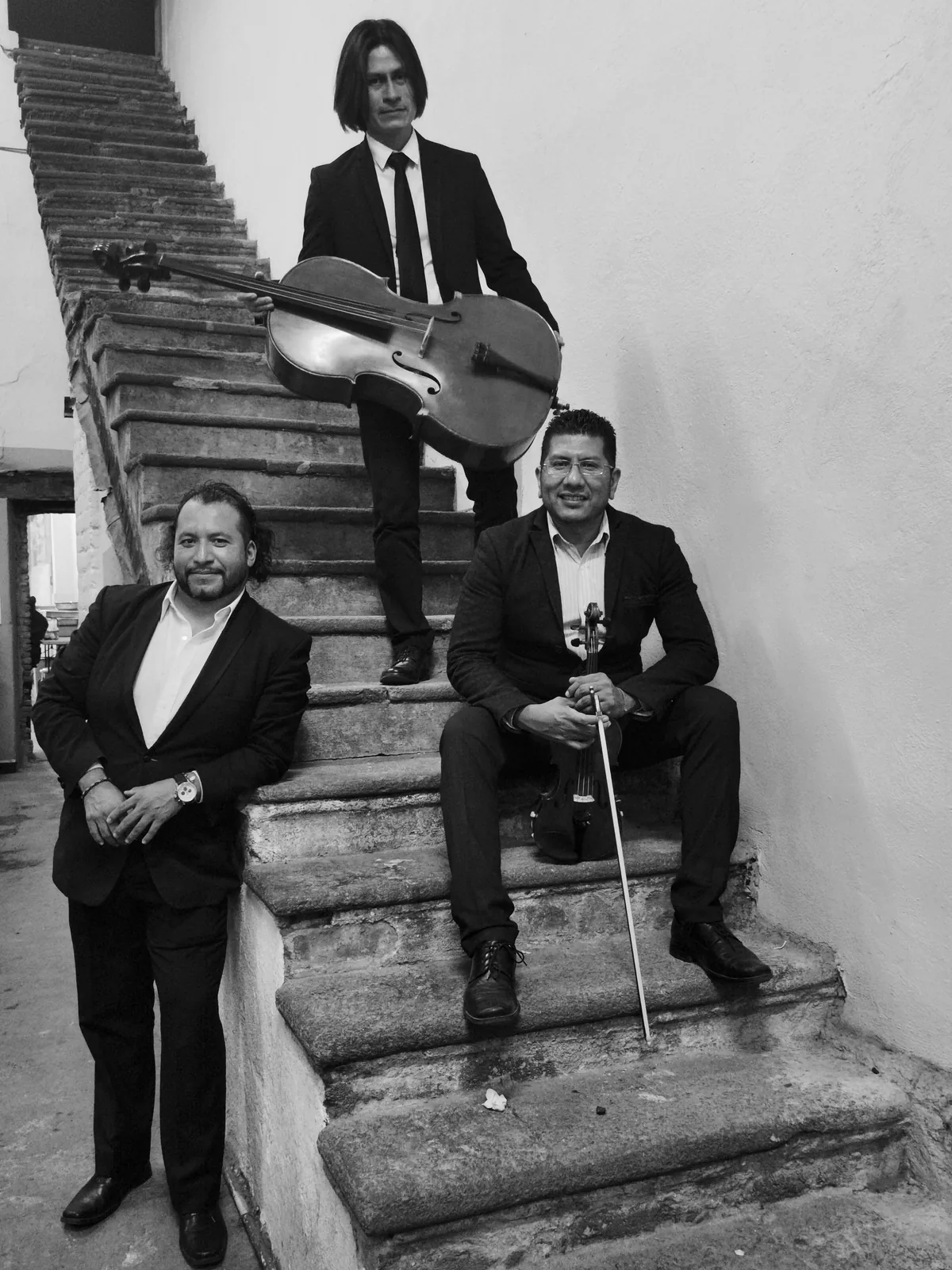 Músicos de piano, violín y violonchelo posando en una escalinata