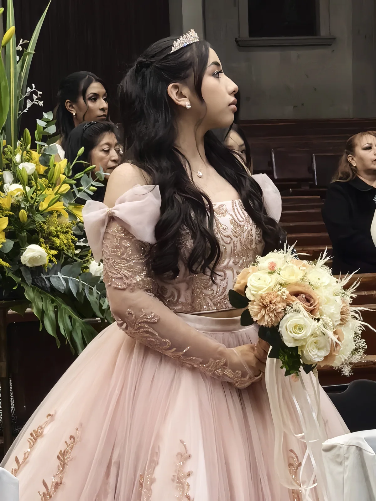 Quinceañera con vestido rosa y ramo durante su ceremonia de XV años en una iglesia