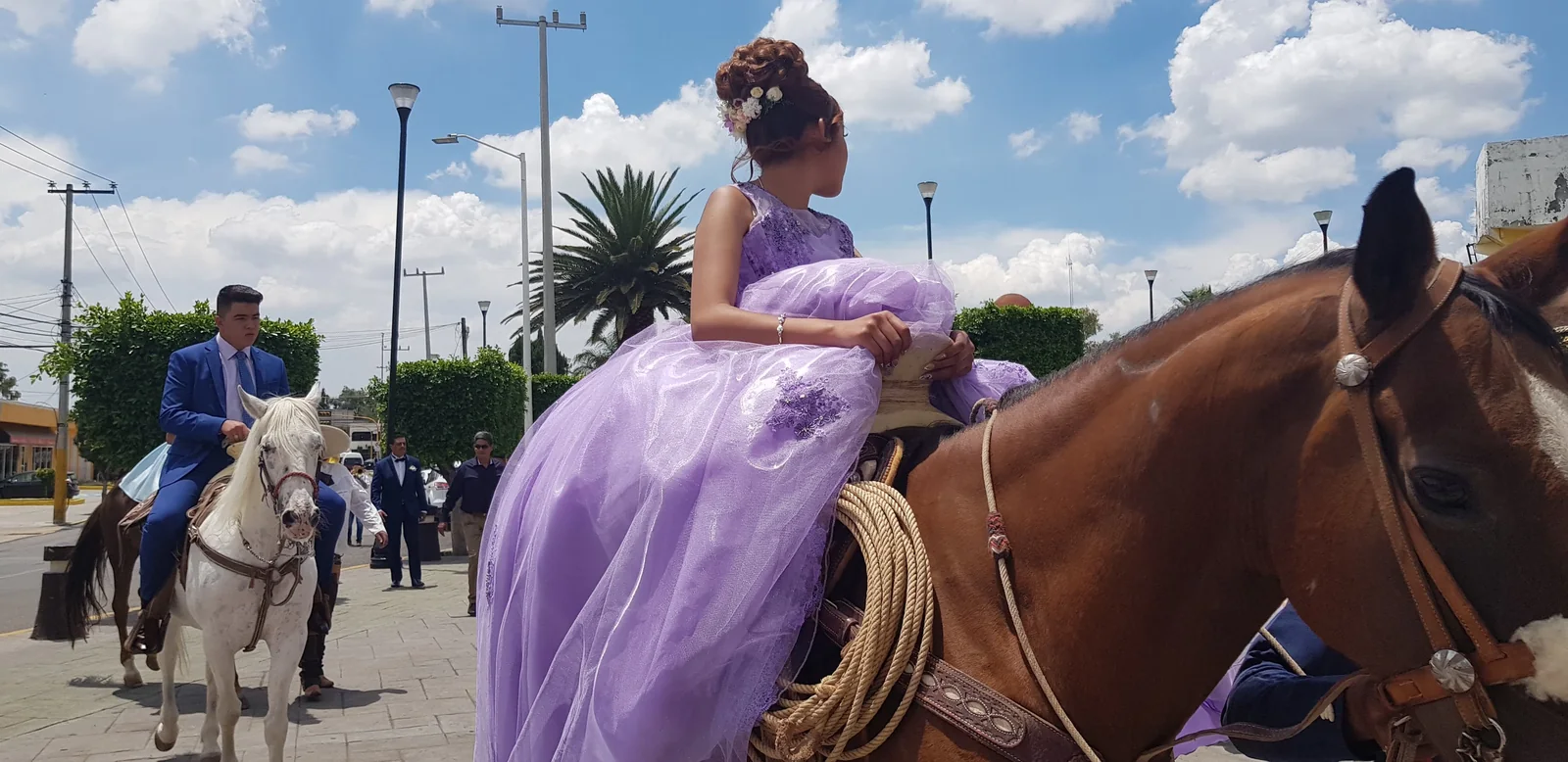 Quinceañera con vestido lila llegando a caballo a su celebración