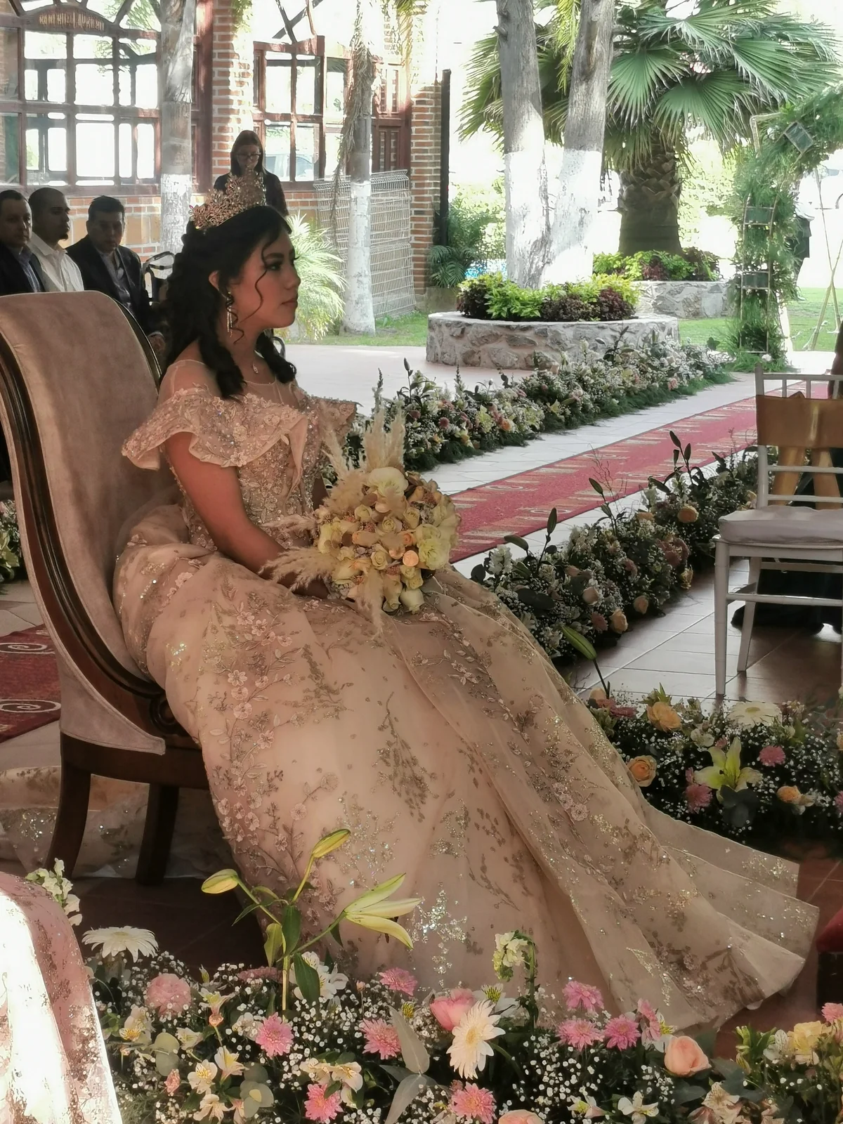 Quinceañera sentada entre flores durante una ceremonia de acción de gracias en jardín