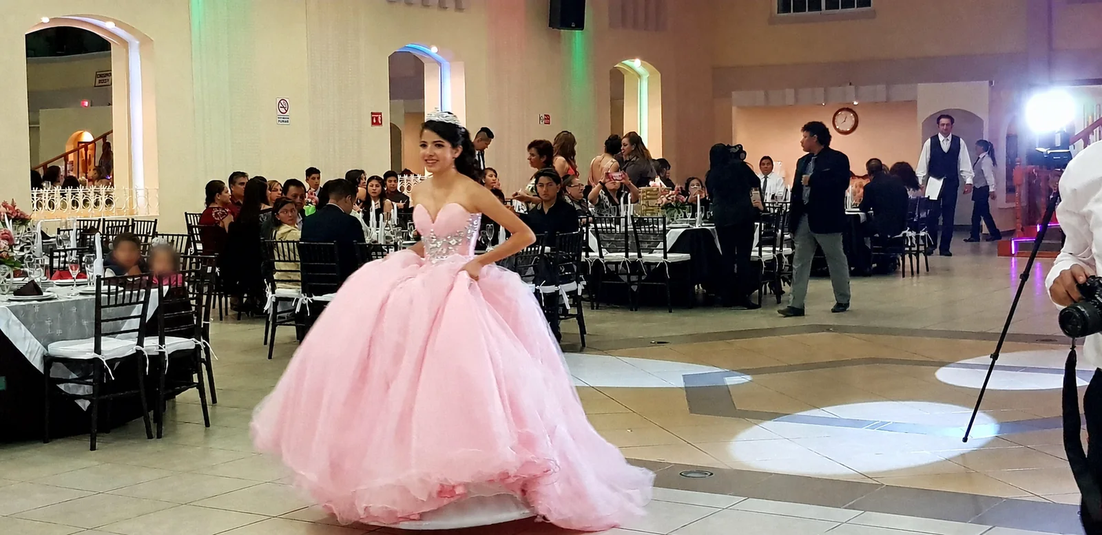Quinceañera con vestido rosa durante el vals en un salón