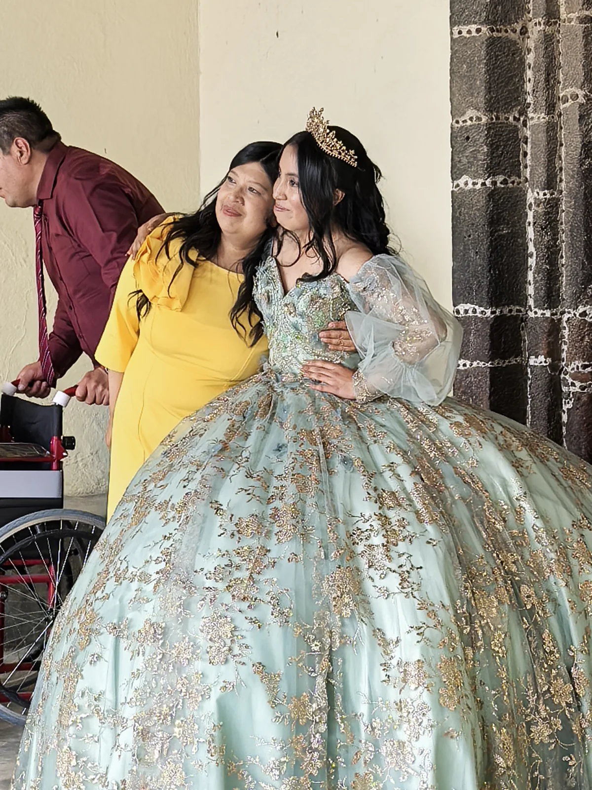 Quinceañera con vestido verde posando con un familiar después de la ceremonia