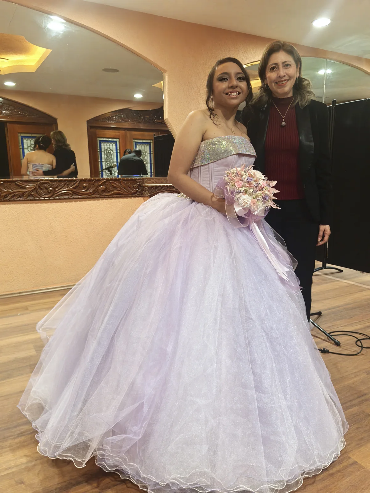 Quinceañera con vestido lila posando junto a la soprano Margarita Rosas