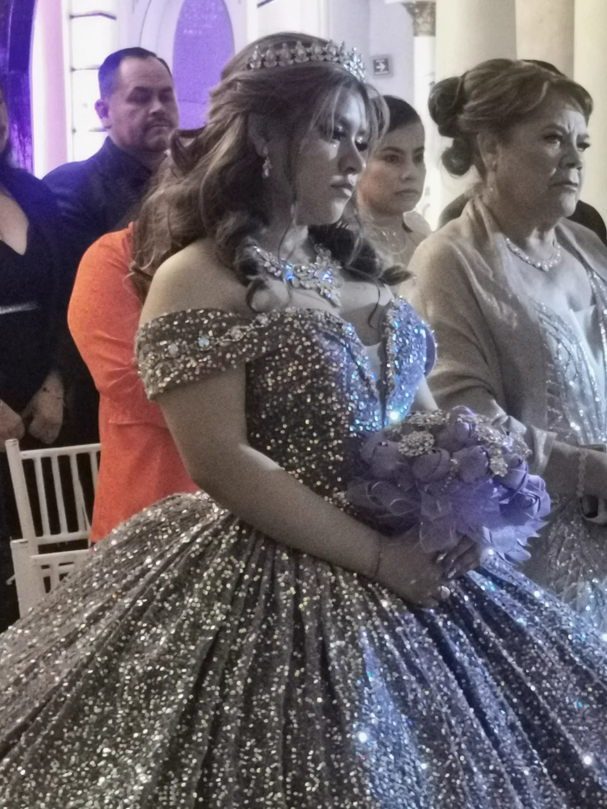 Quinceañera con vestido brillante y ramo durante su ceremonia