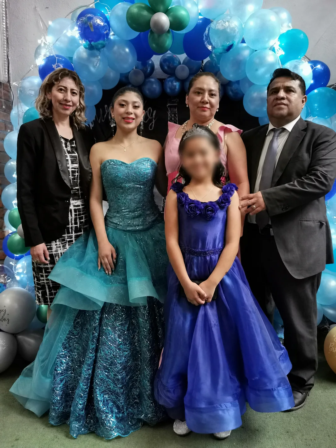 Quinceañera con vestido verde y su familia durante la celebración